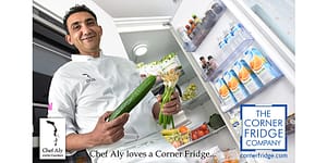 Chef Aly holding a cucumber and celery with an open cold room behind him